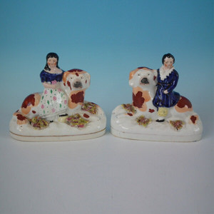 Pair Staffordshire Children seated on recumbent spaniels