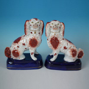 Pair Staffordshire pottery spaniels, russet & white on blue bases