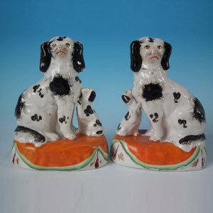 Pair Staffordshire pottery spaniels with pups on cushion